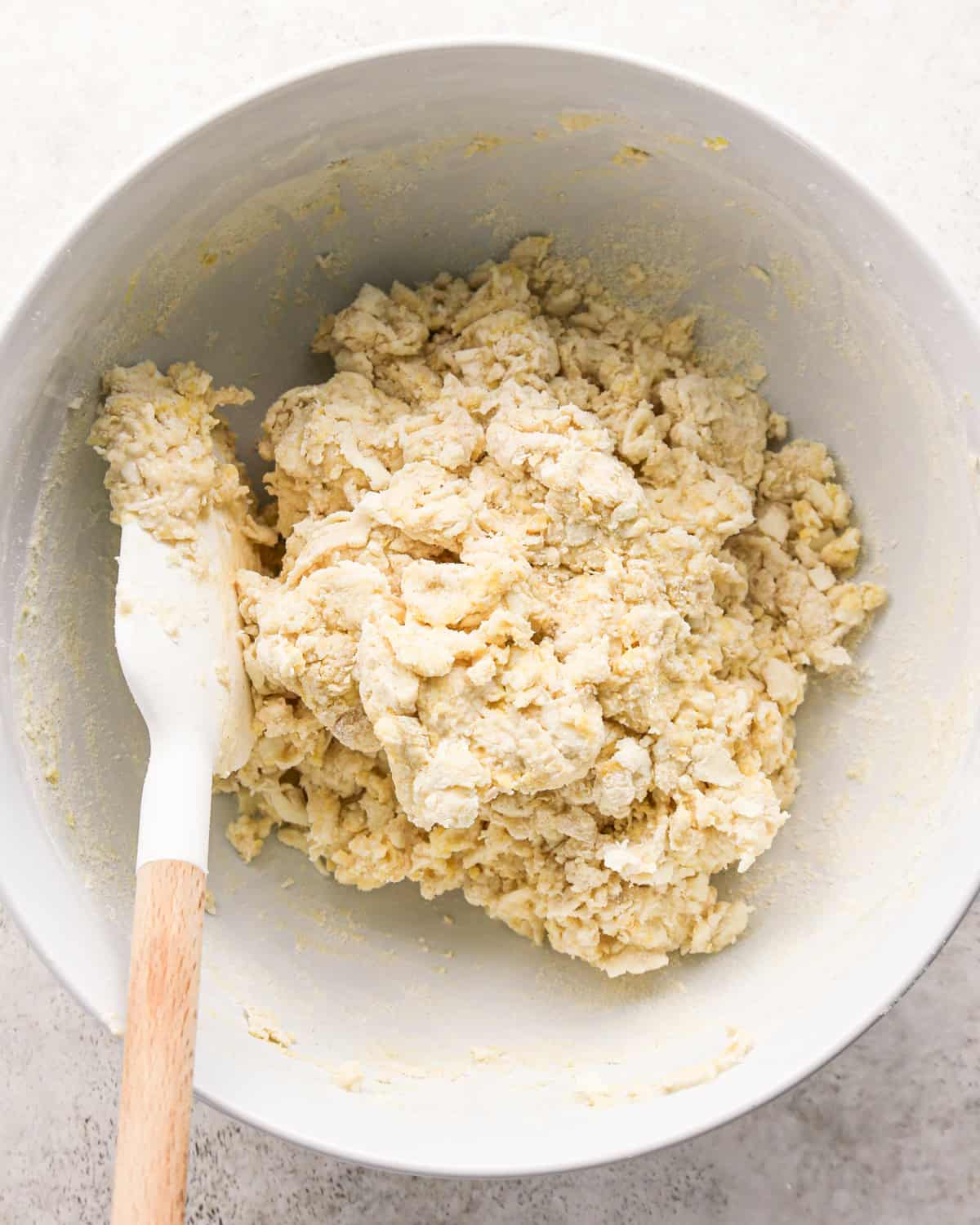 how to make cherry scones - dough after mixing in a white bowl with a white and wood spatula
