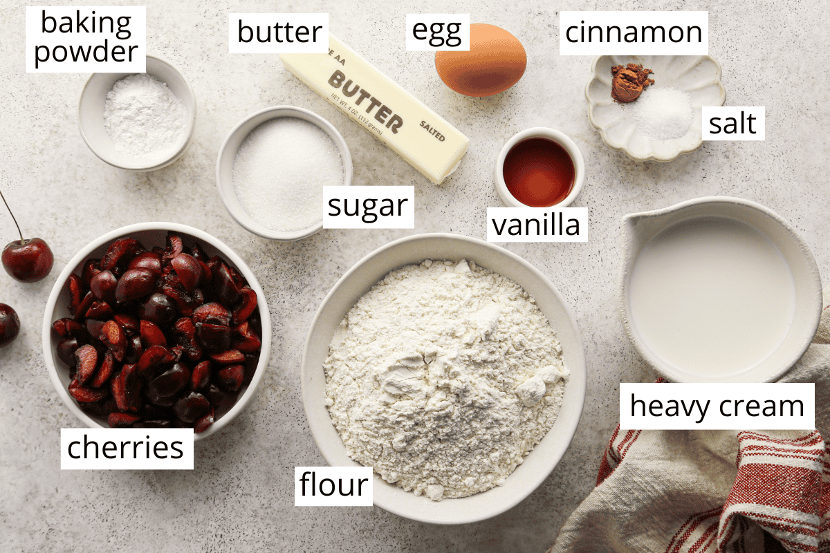 overhead photo of the labeled ingredients in this cherry scones recipe like flour, cherries, vanilla, sugar, butter and more. 