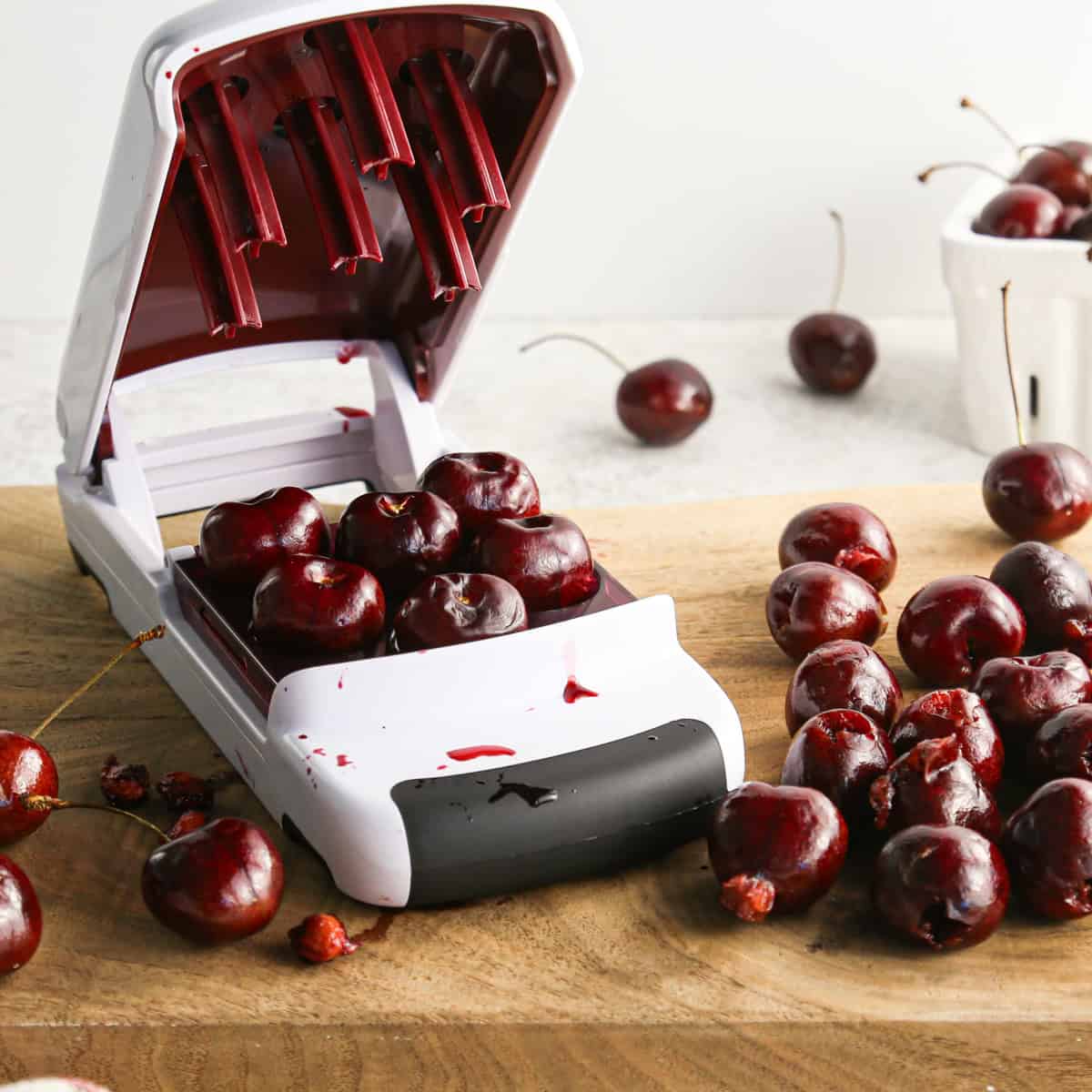 cerises étant dénoyautées avec un dénoyauteur sur une planche à découper en bois