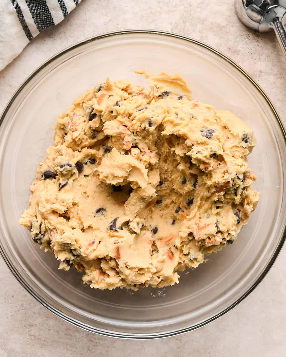 chocolate chip pretzel cookies dough in a glass container to chill