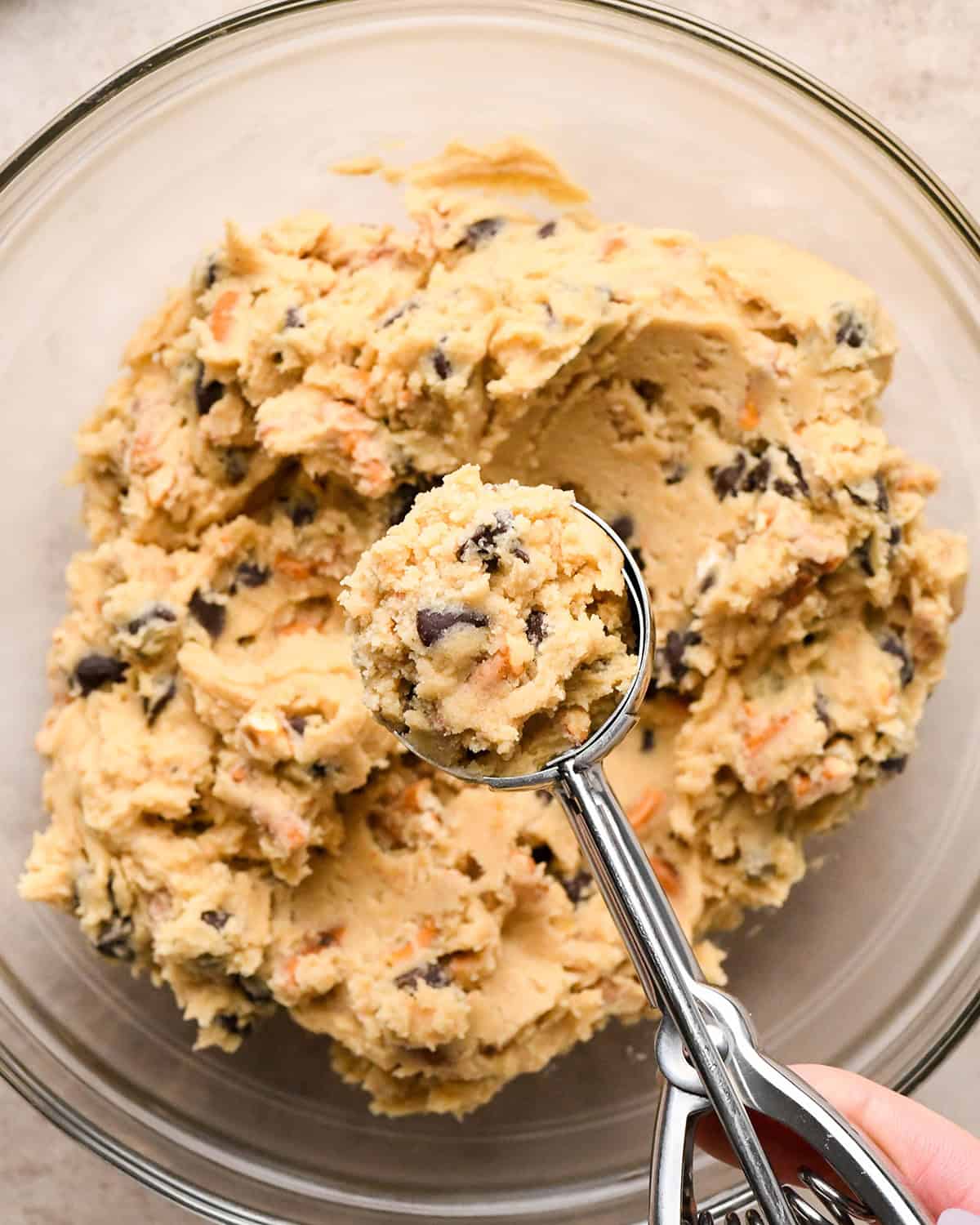 a cookie scoop with a scoop of chocolate chip pretzel cookie dough in it