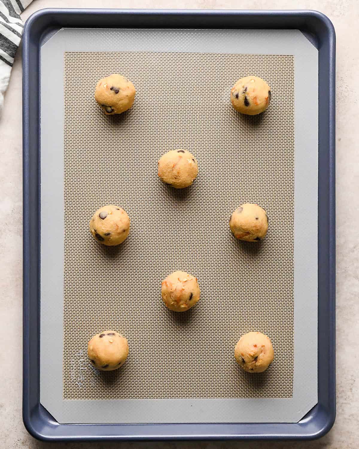 8 balls of chocolate chip pretzel cookies dough on a baking sheet before baking