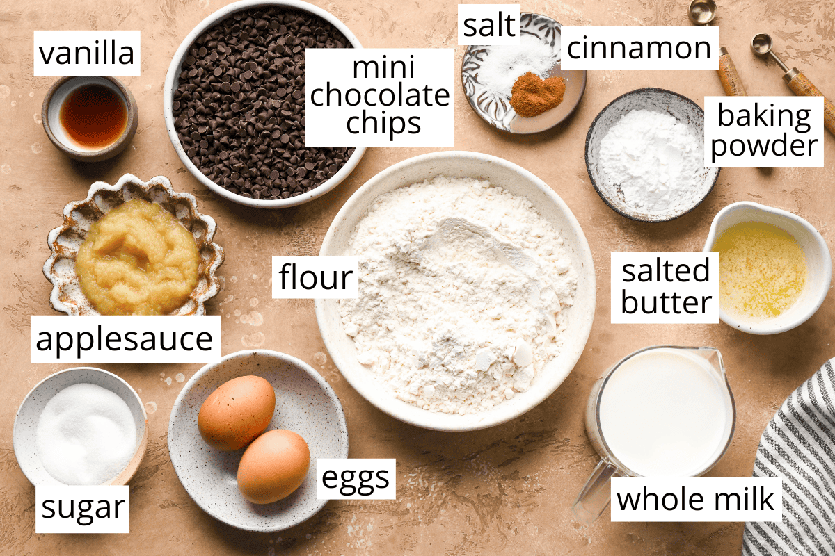 overhead photo of the labeled ingredients in this Chocolate Chip Waffles recipe like flour, milk, eggs, butter, applesauce, and mini chocolate chips