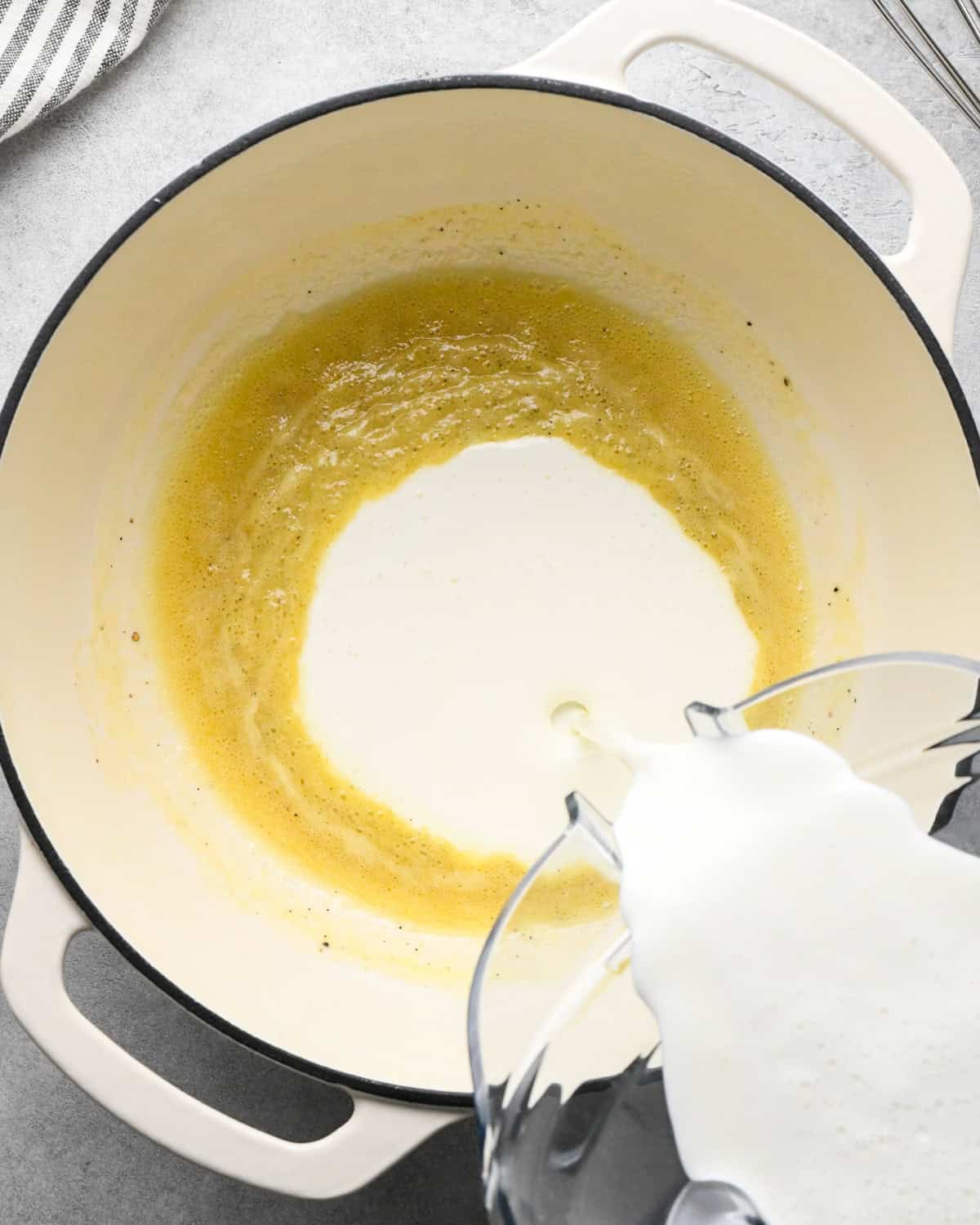 the blended cottage cheese and milk mixture being poured into the cooked butter/flour mixture making cottage cheese macaroni and cheese
