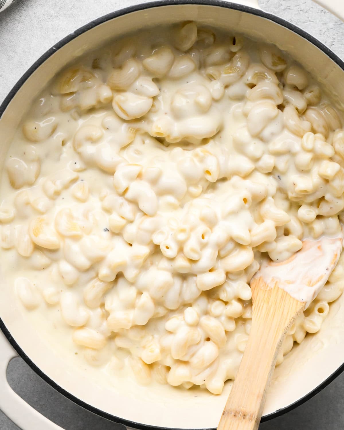 cottage cheese mac and cheese in a white saucepan with a wooden spatula