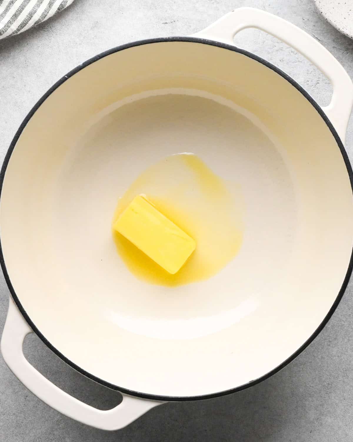 a stick of butter in a white saucepan making cottage cheese mac and cheese