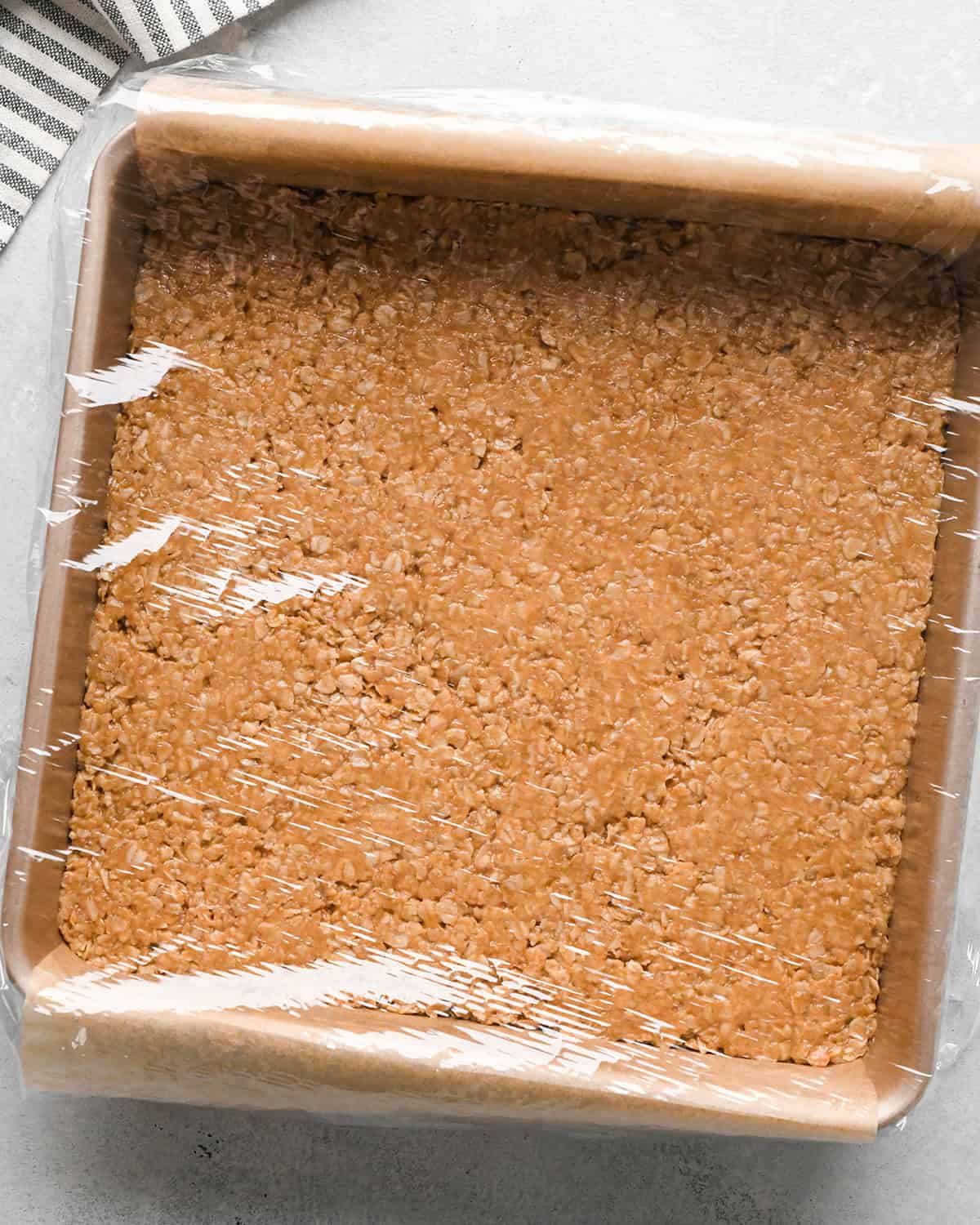 Peanut Butter Granola Bars in the pan covered with plastic wrap