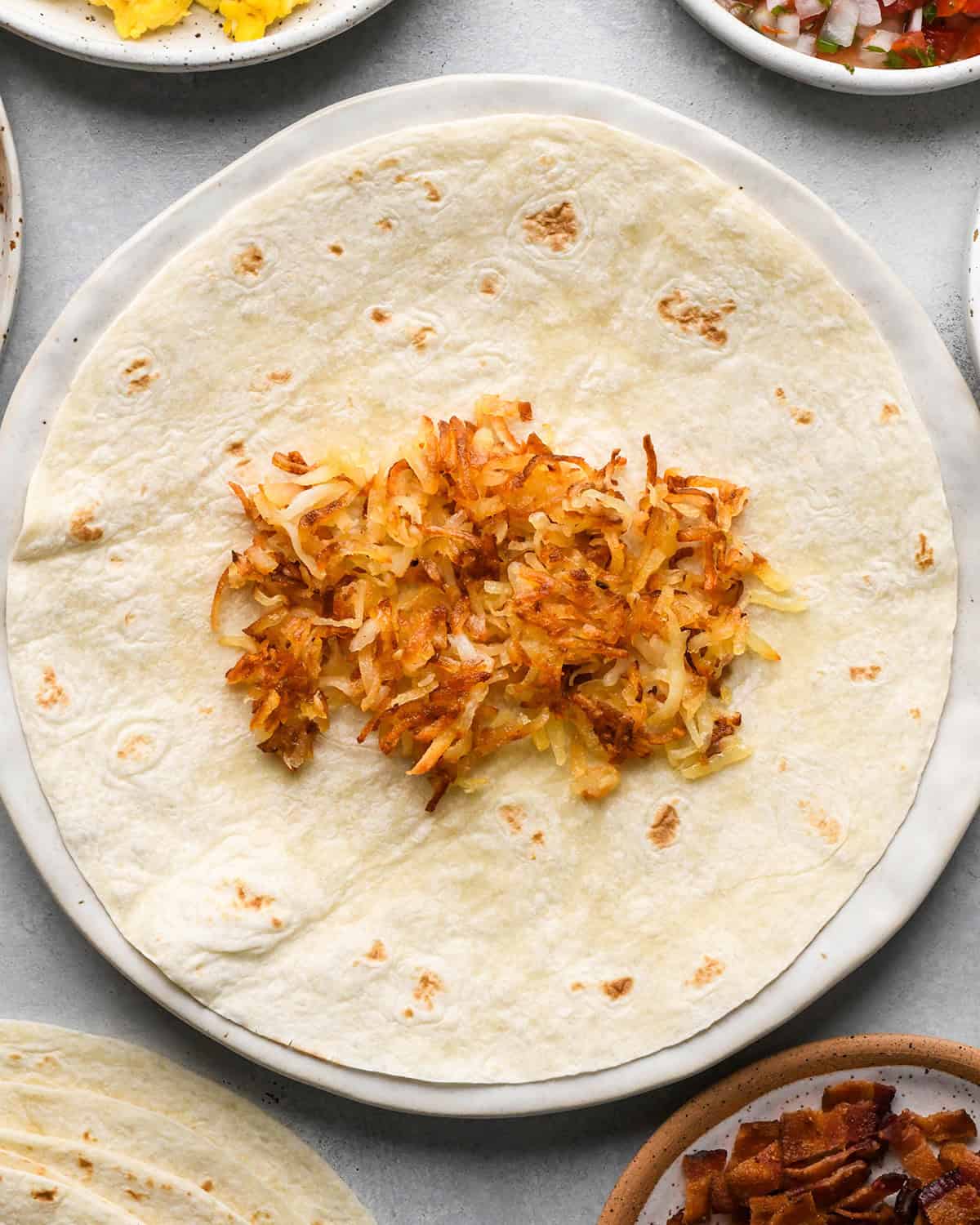 assembling a breakfast burrito - hash browns on the tortilla