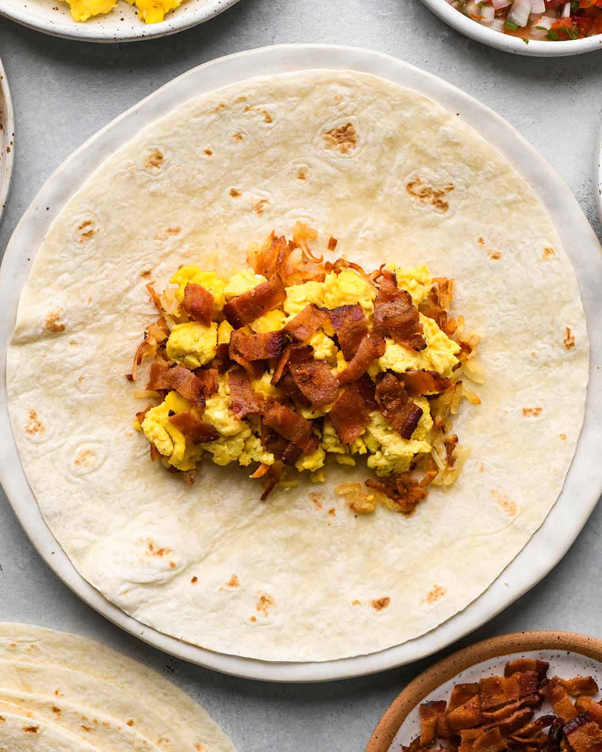assembling a breakfast burrito - adding bacon