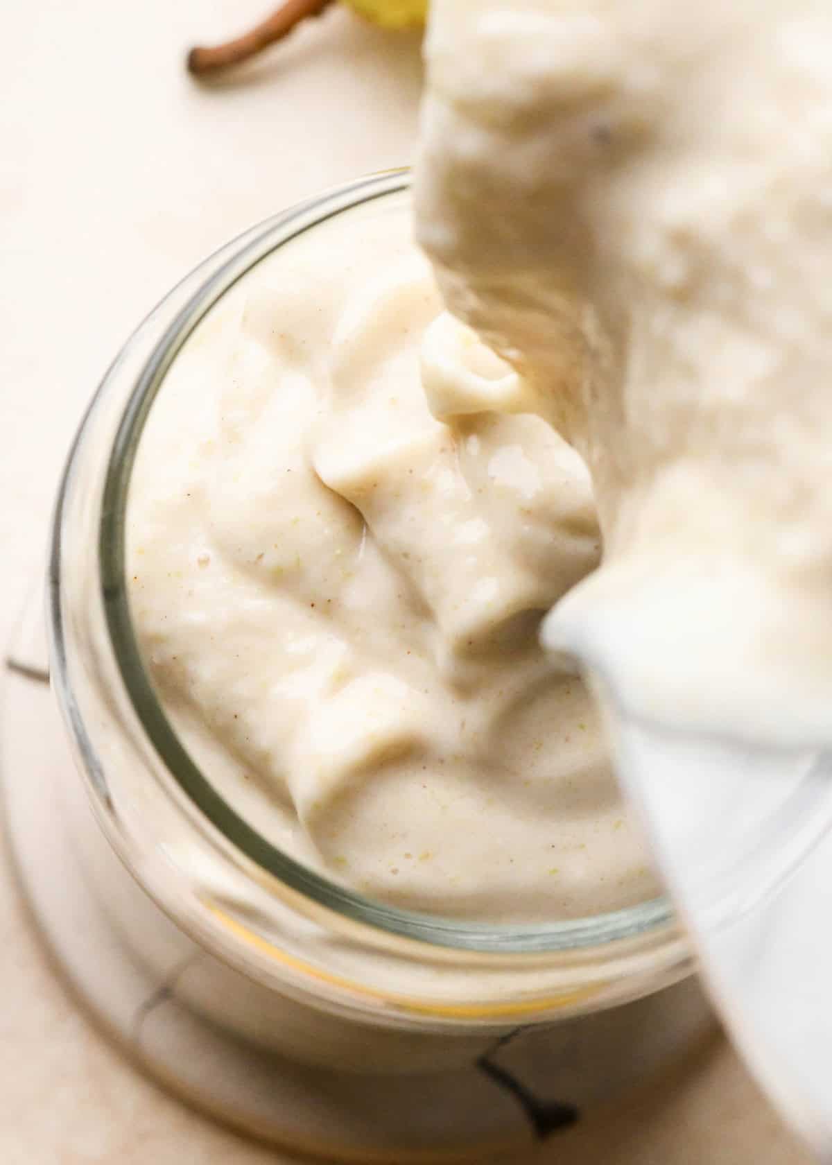 Pear Smoothie being poured into a glass from the blending container