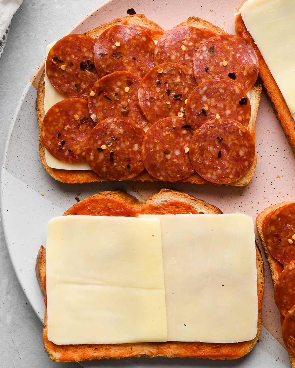 making Pizza Grilled Cheese - crushed red pepper sprinkled over the pepperoni on one piece of bread