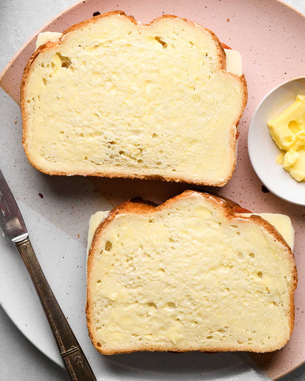 two assembled pizza grilled cheese sandwiches spread with butter before cooking