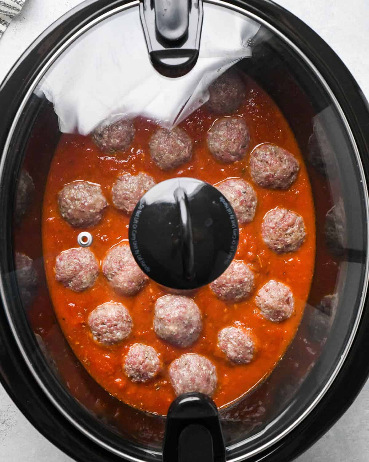 making slow cooker meatballs - ingredients in the slow cooker before cooking with a glass lid on