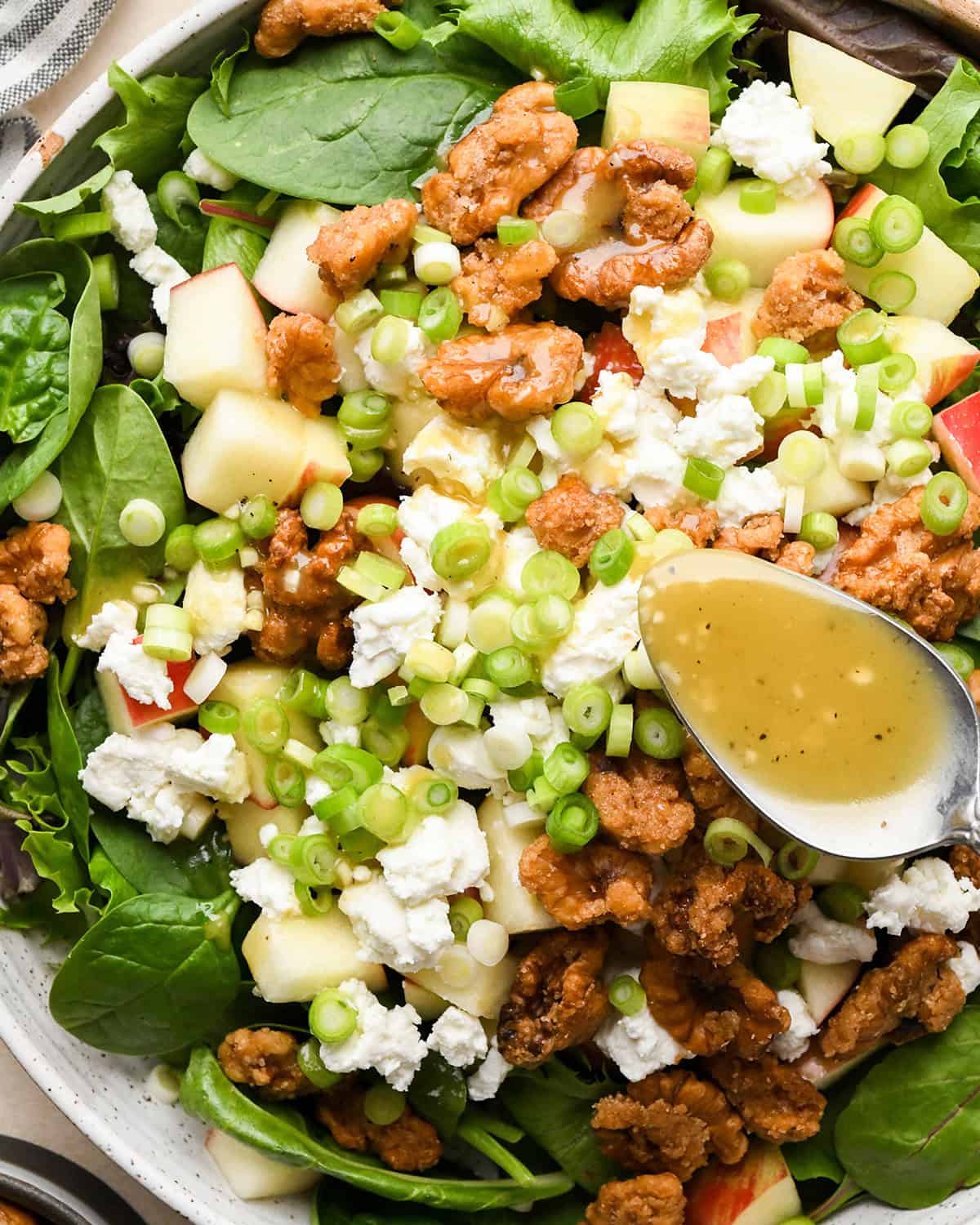assembling apple salad - dressing being poured over the salad