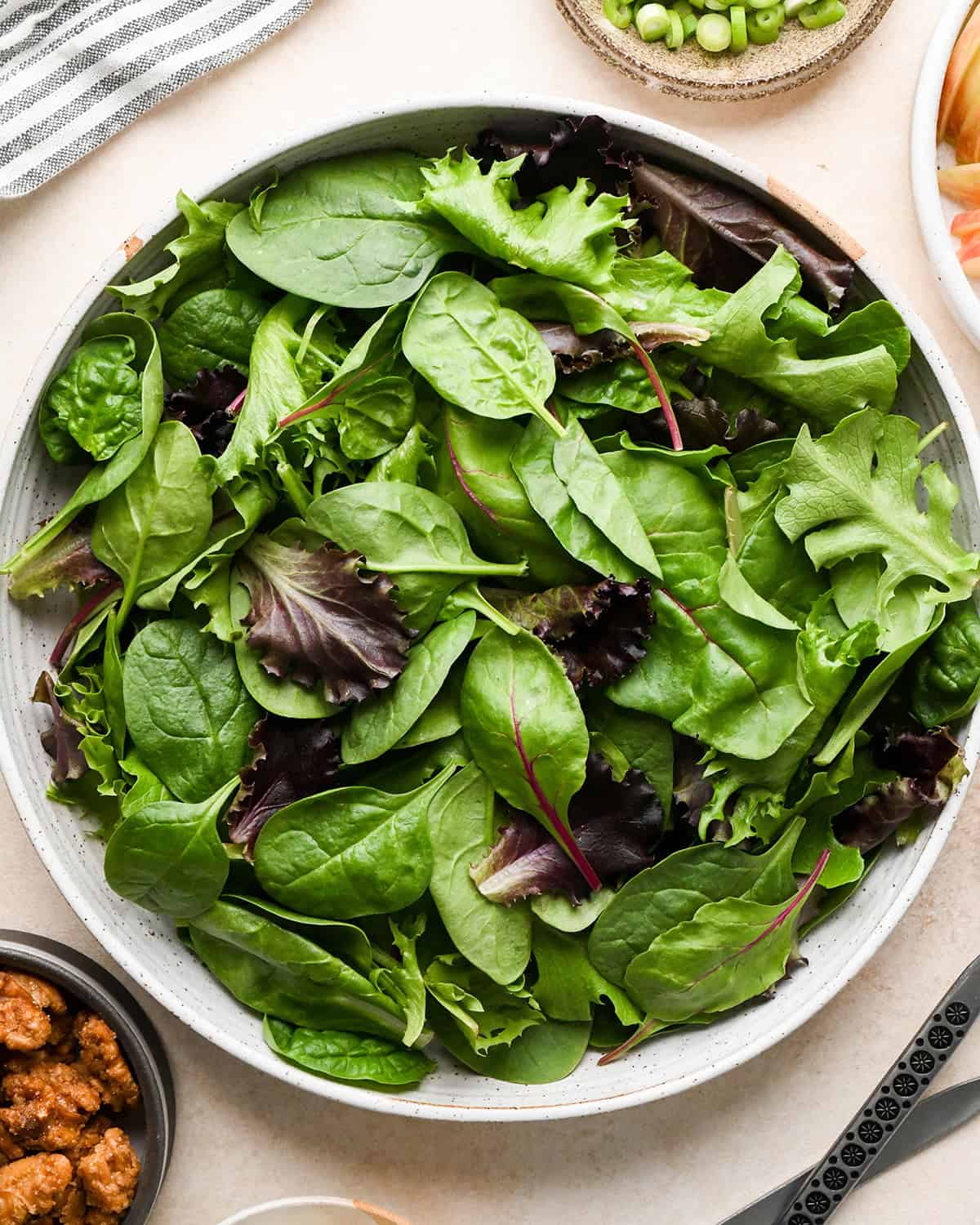 assembling apple salad - spring mix in a bowl