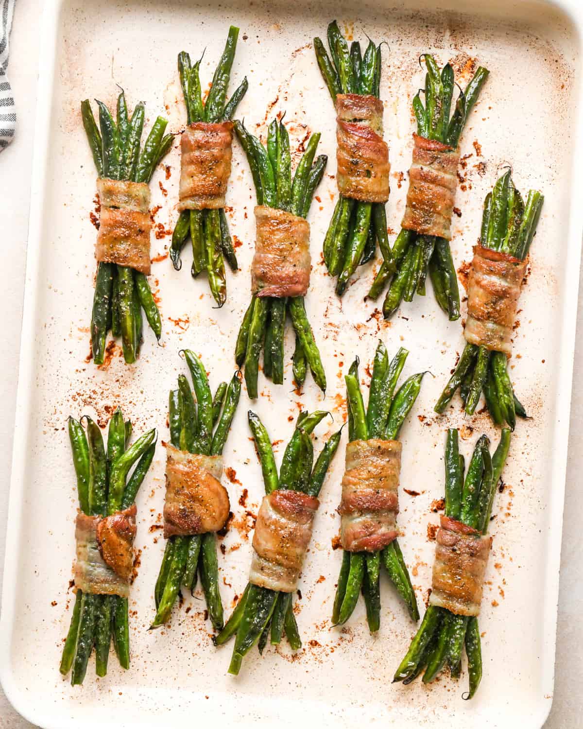11 bundles of Bacon Wrapped Green Beans on a baking sheet after baking
