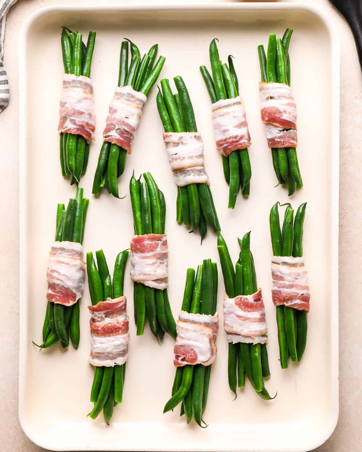 11 Bacon Wrapped Green Beans bundles on a baking sheet before baking