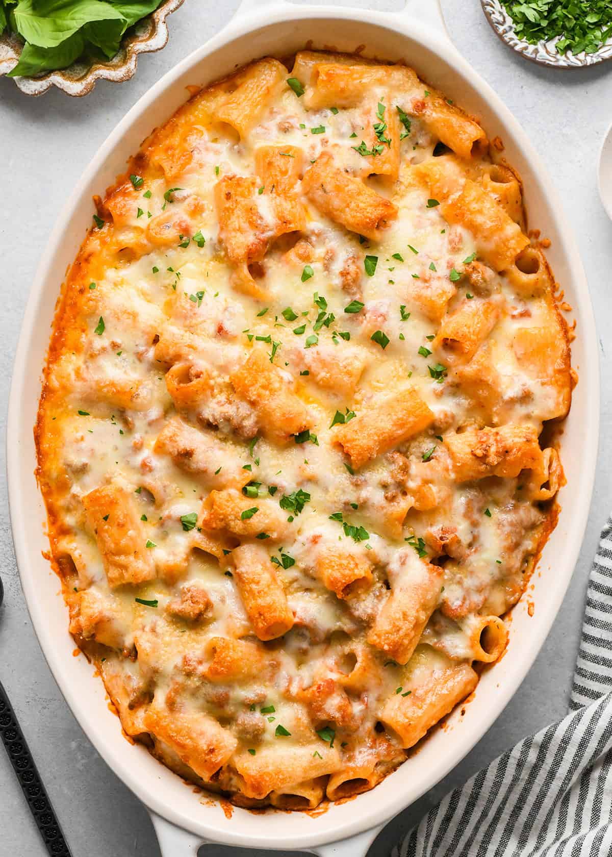 Baked Mostaccioli in a white baking dish garnished with chopped parsley