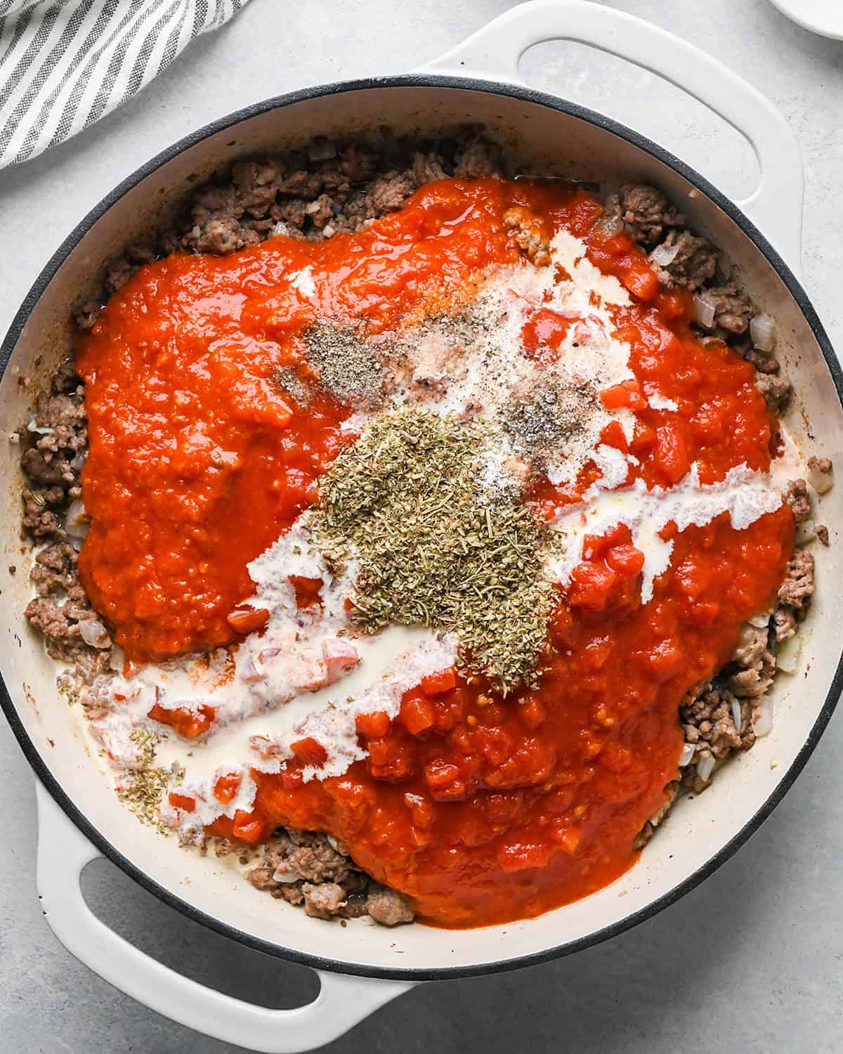 making Baked Mostaccioli - tomatoes, marinara sauce, cream and seasonings added to ground beef mature before stirring