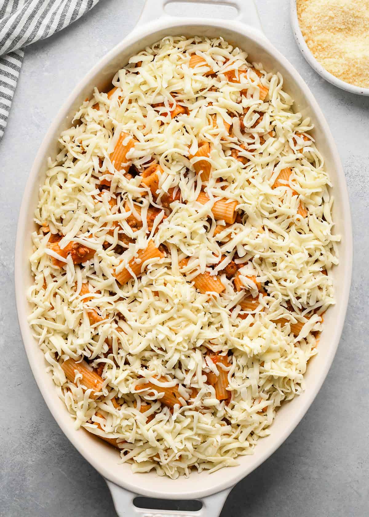 mozzarella cheese sprinkled over Baked Mostaccioli mixture in a white baking dish 