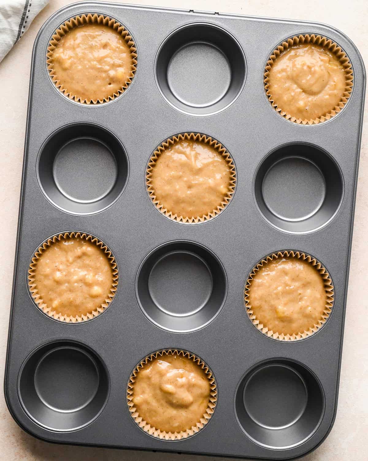a muffin pan with 6 wells filled with liners and banana crumb muffin batter