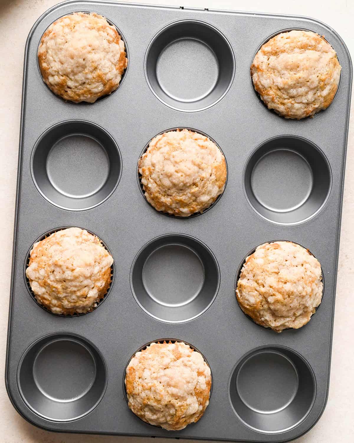 6 banana crumb muffins in a muffin pan after baking