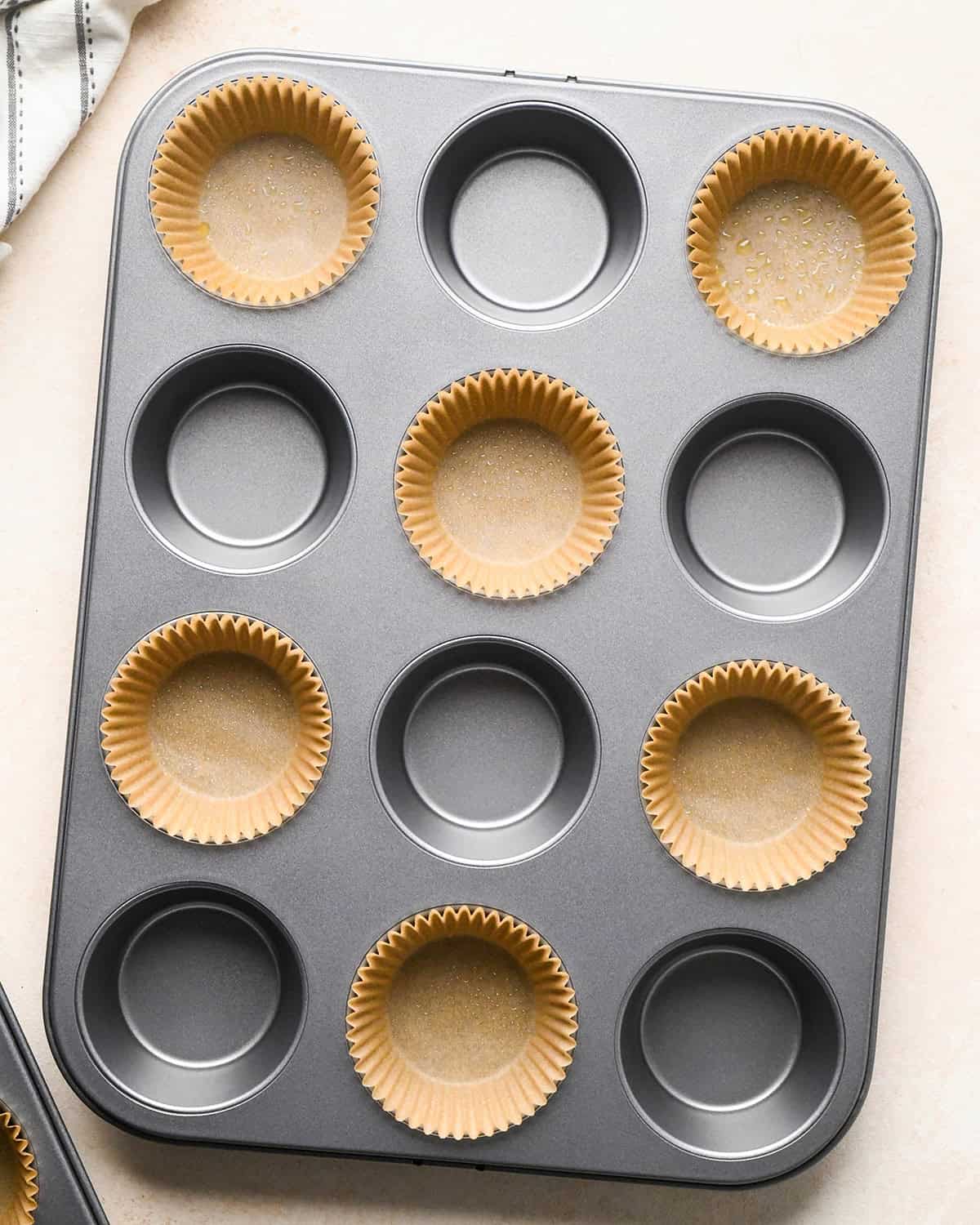 a muffin pan with 6 wells lined and greased
