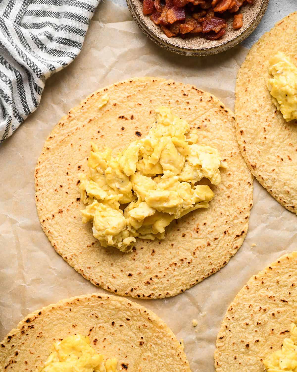 assembling breakfast tacos - scrambled eggs on tortillas