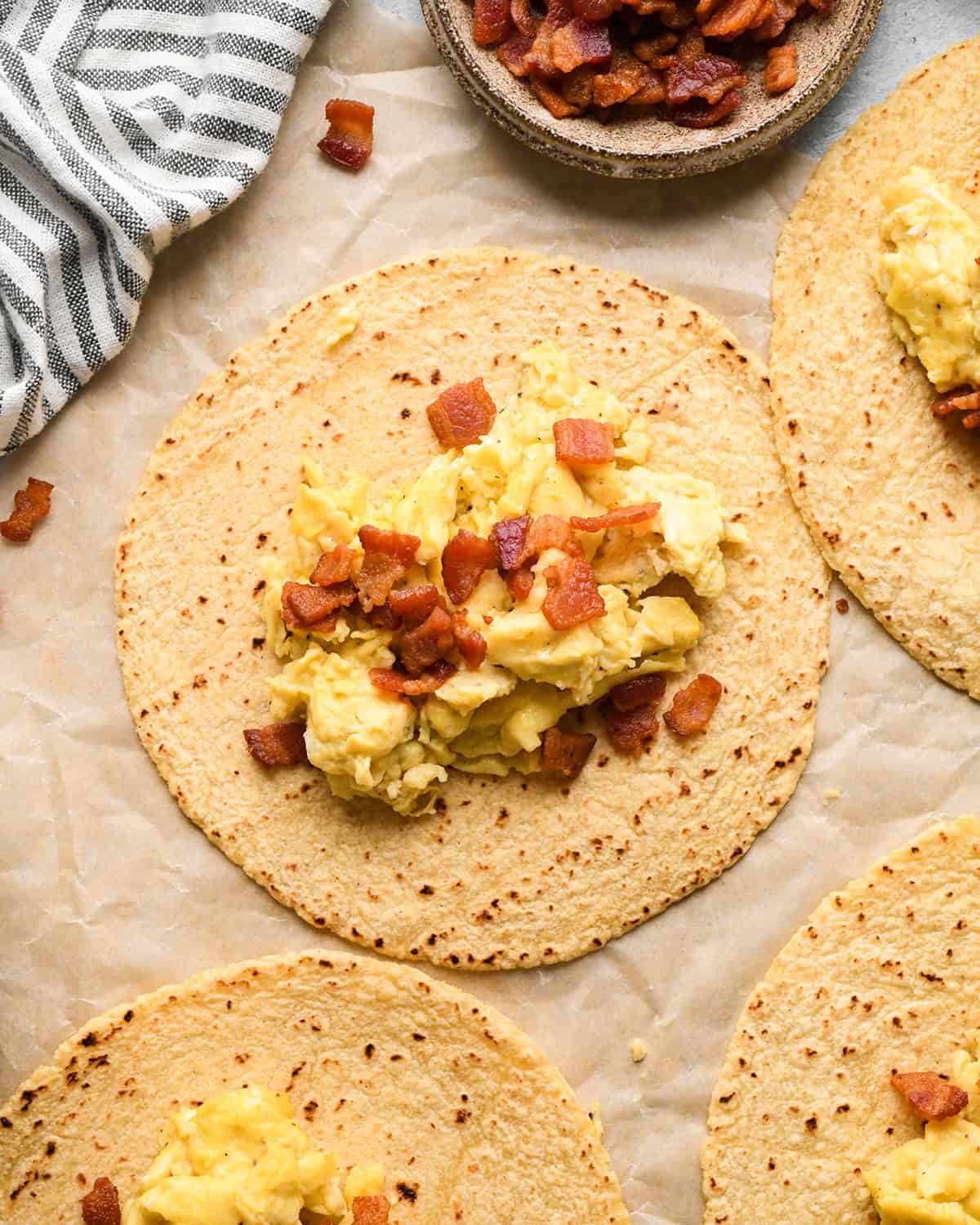 assembling breakfast tacos - bacon put on top of the eggs