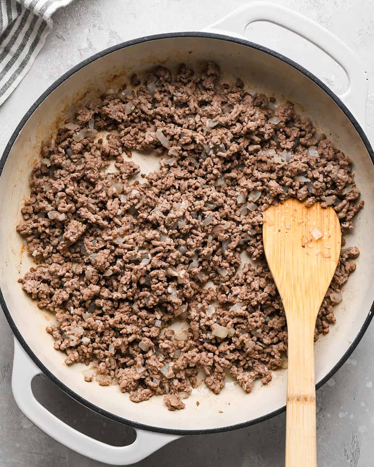 making Ground Beef Tortellini - ground beef & onion mixture cooked in a pan with a wooden spatula