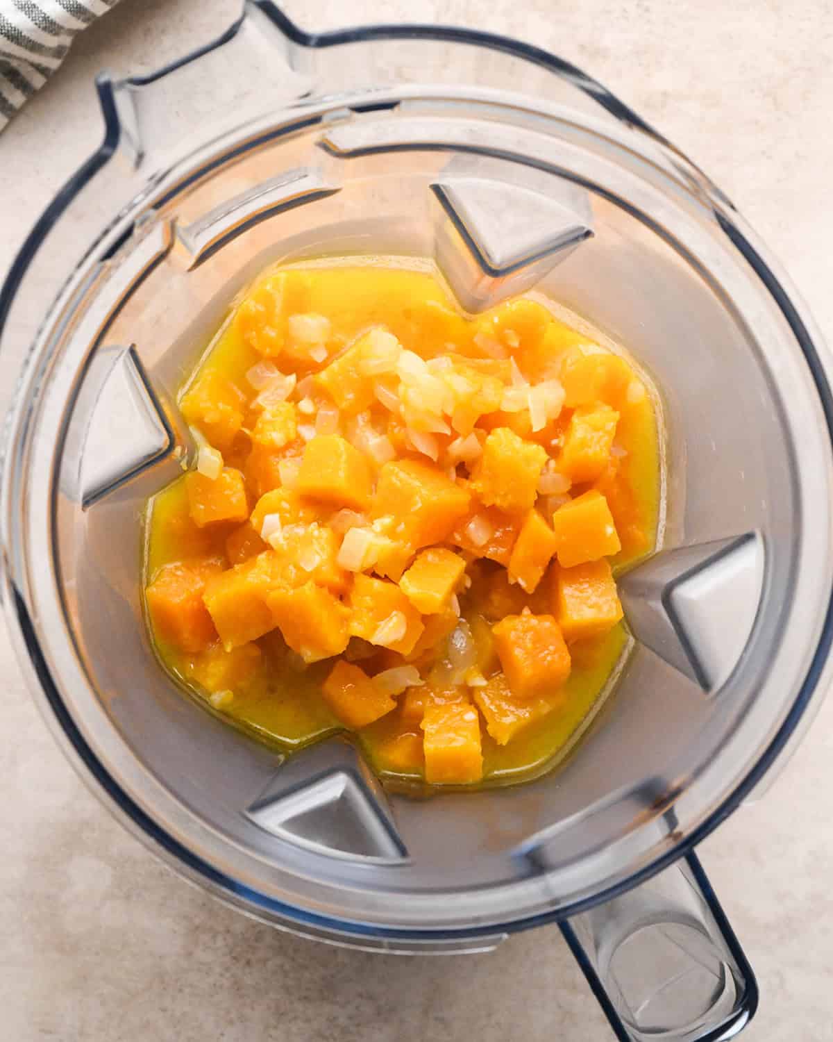 Making butternut squash risotto - butternut squash, garlic, onion, butter, and chicken broth placed in a clear blender