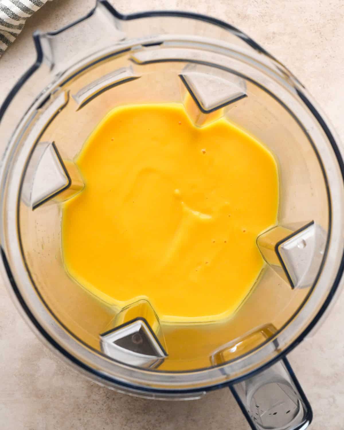 Making butternut squash risotto - butternut squash, garlic, onion, butter, and chicken broth placed in a clear blender and blended up until smooth