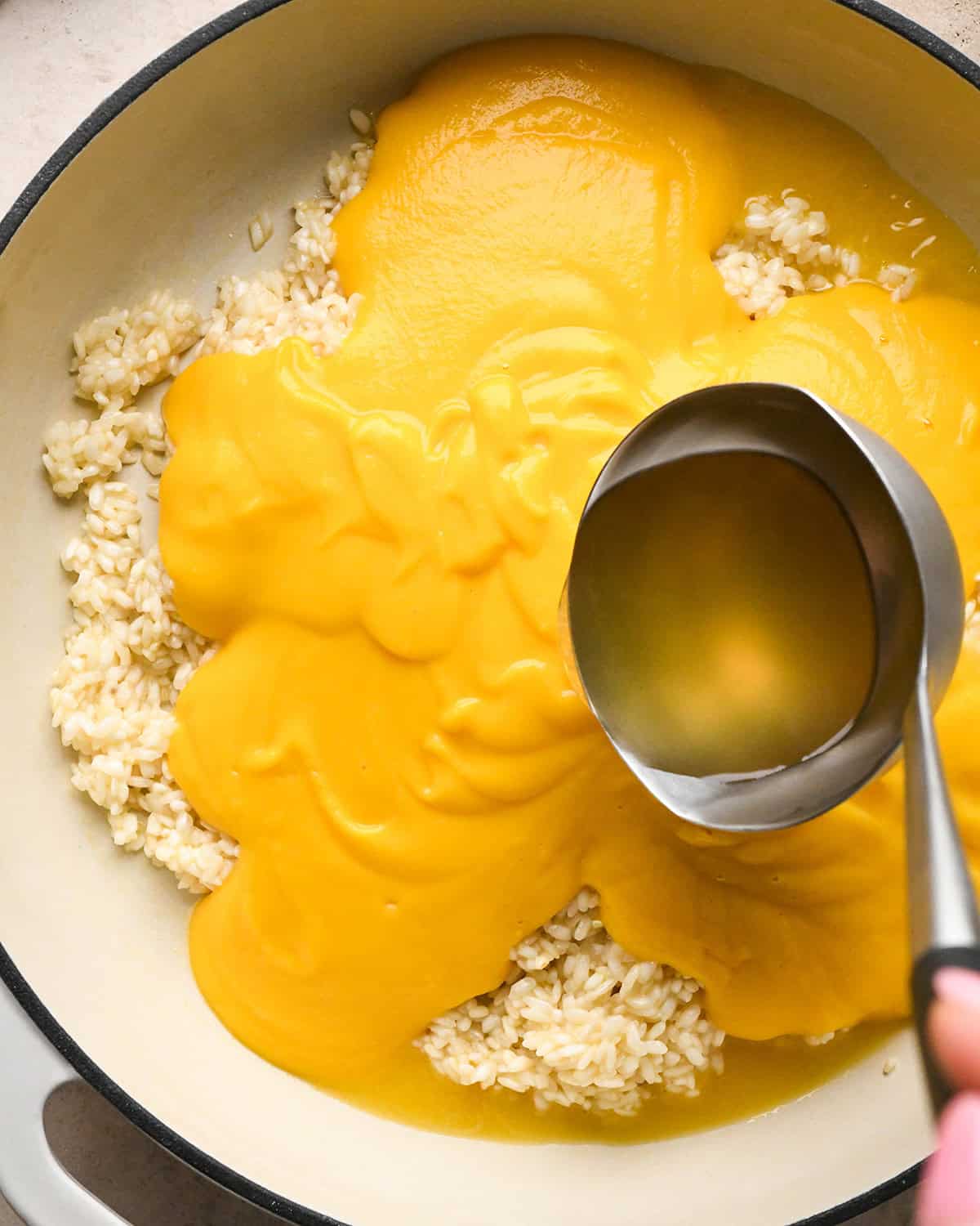 Making butternut squash risotto - adding chicken broth to a saucepan with butternut squash mixture and cooked rice