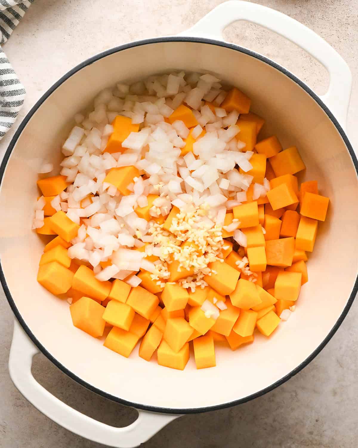 Making butternut squash risotto - butternut squash, garlic, onion, and butter in a white 5-quart saucepan, uncovered 