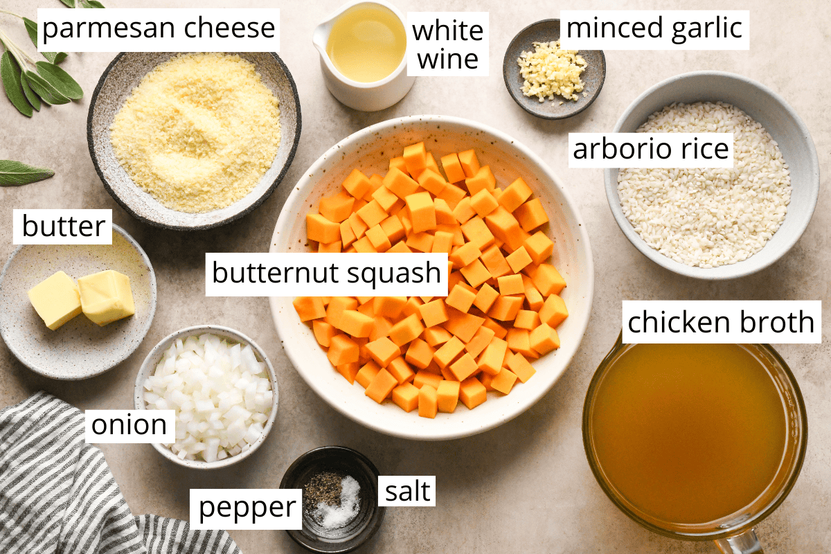 Overhead photo of the labeled ingredients in this butternut squash risotto recipe like butternut squash, parmesan cheese, chicken broth, white wine, butter, minced garlic, rice, onion, salt, and pepper
