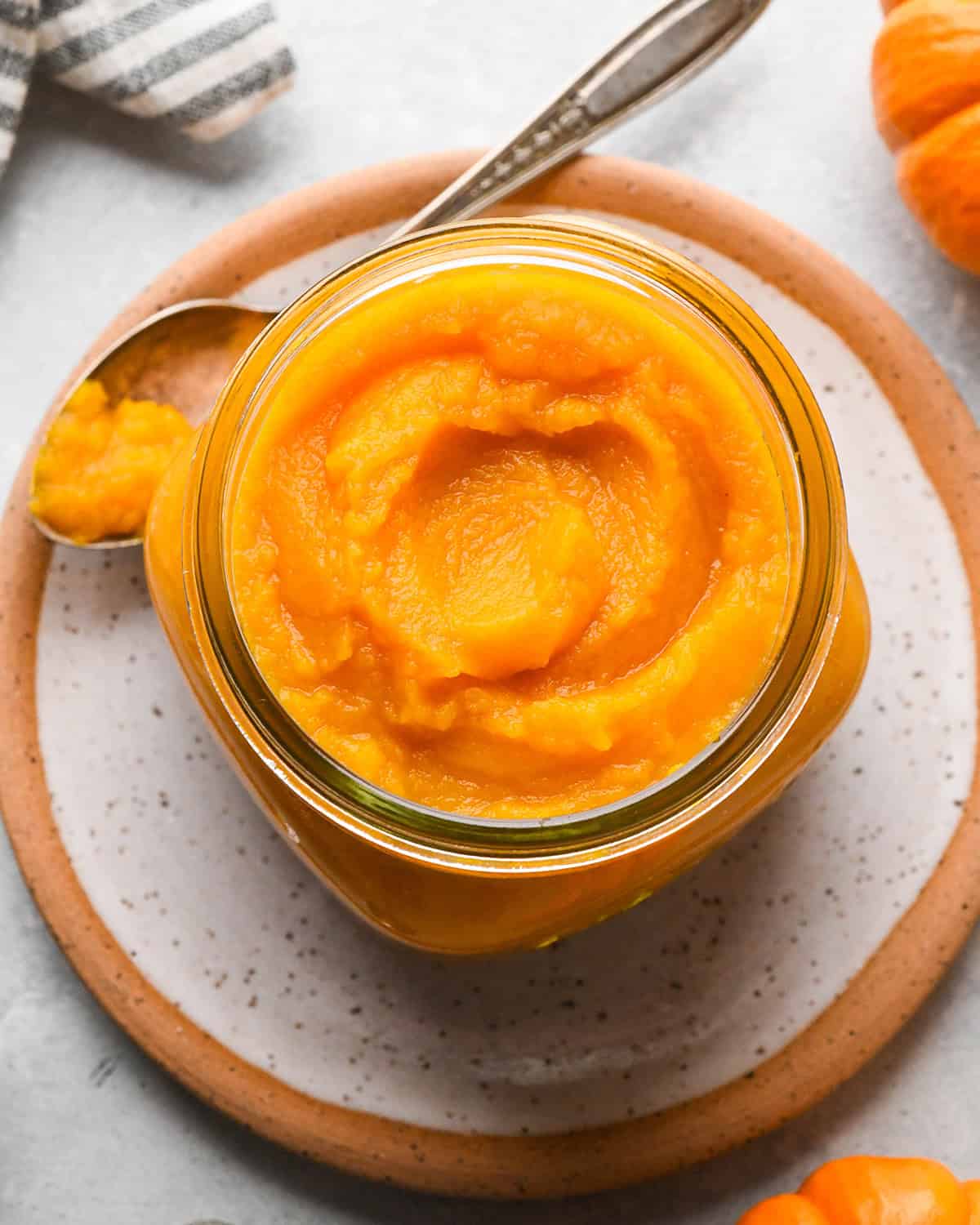 homemade pumpkin puree in a glass jar with a spoon of puree next to it