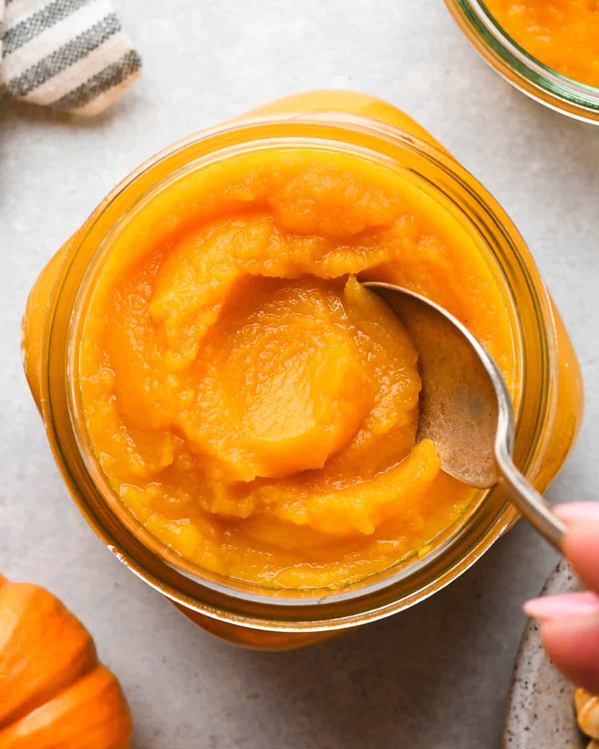 up close photo of homemade pumpkin puree in a glass jar with a spoon