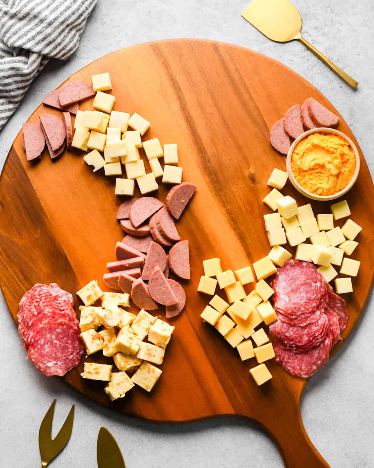assembling a charcuterie board - meat added near cheeses