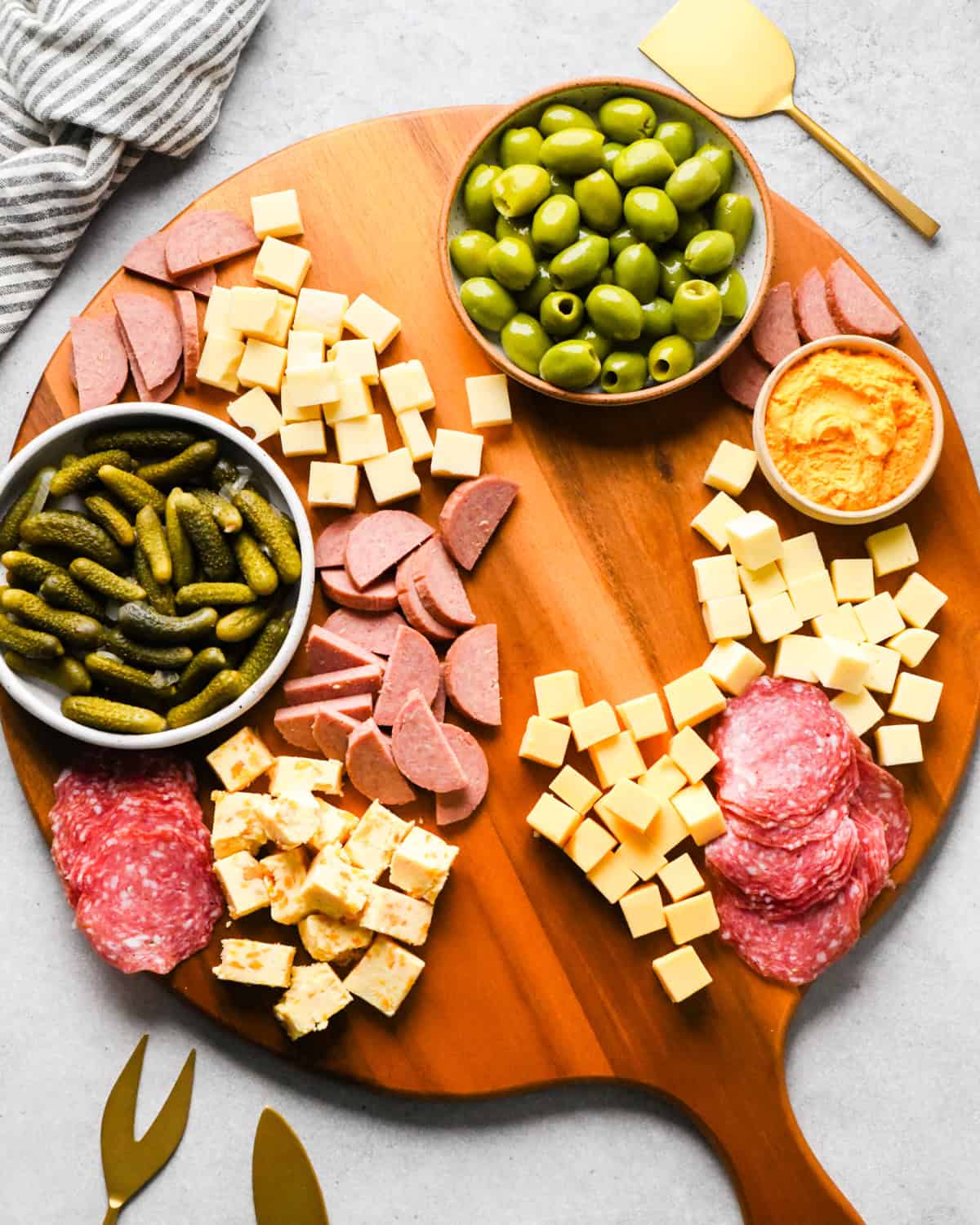 assembling a charcuterie board - a bowl of pickles and a bowl of olives added