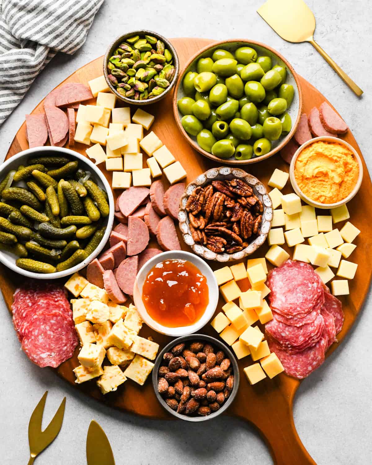 assembling a charcuterie board - bowls of nuts and a bowl of jam added to the board