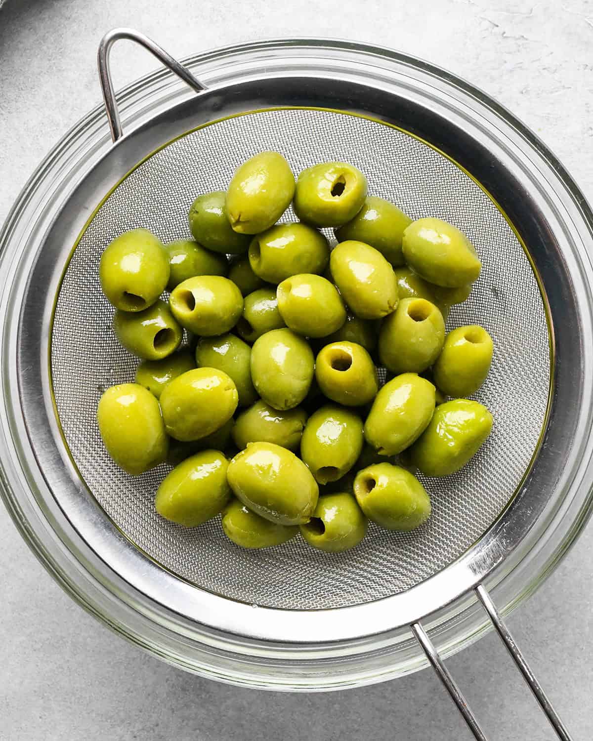 green olives in a metal strainer