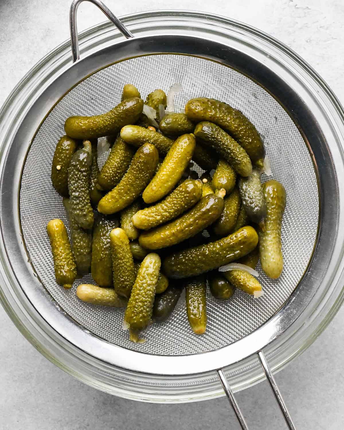small pickles in a metal strainer