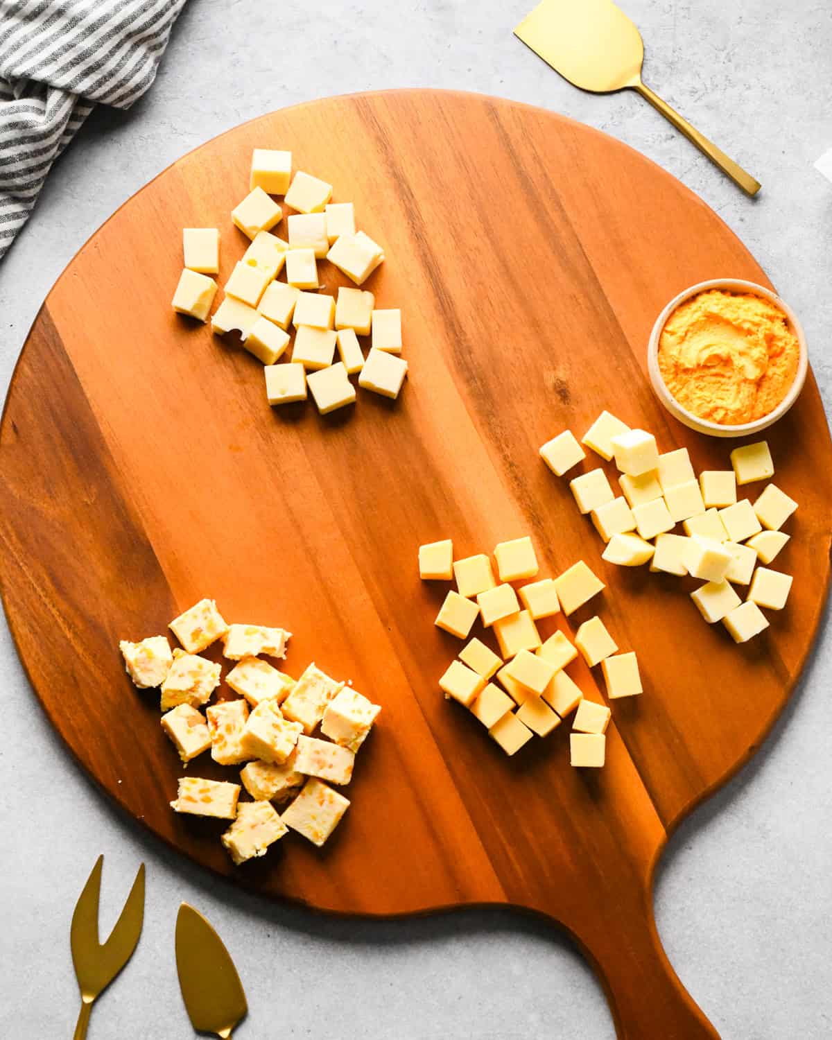 How to Make a Charcuterie Board - cubed cheese arranged spaced out on a round wood board