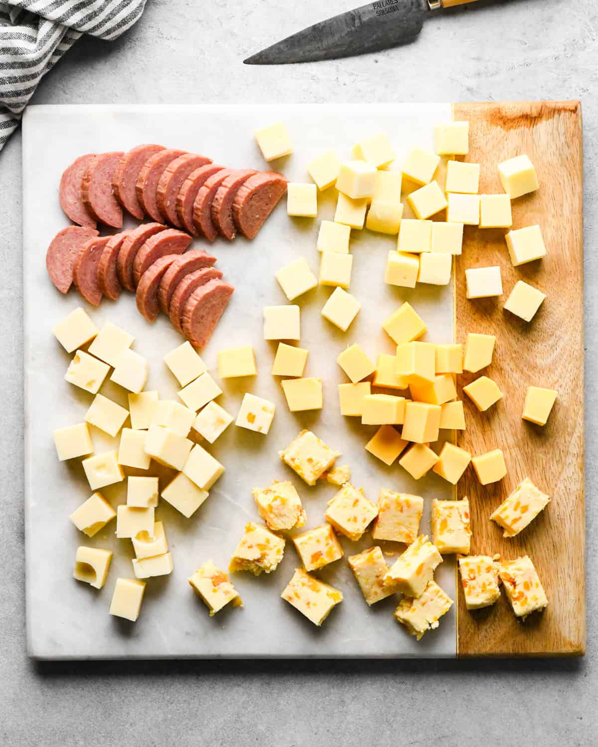 How to Make a Charcuterie Board - cubed cheese and sliced summer sausage on a cutting board
