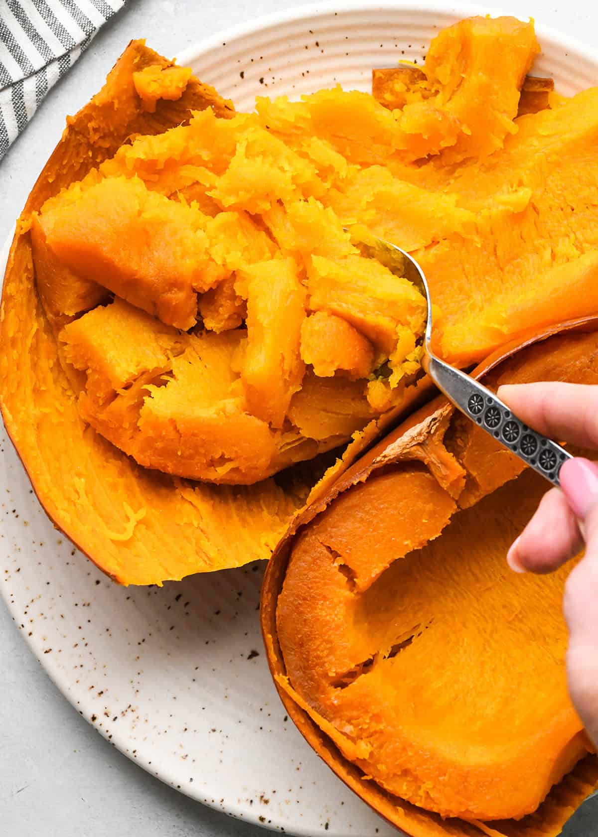 How to Make Pumpkin Puree - a spoon scooping out the pulp of a baked pie pumpkin