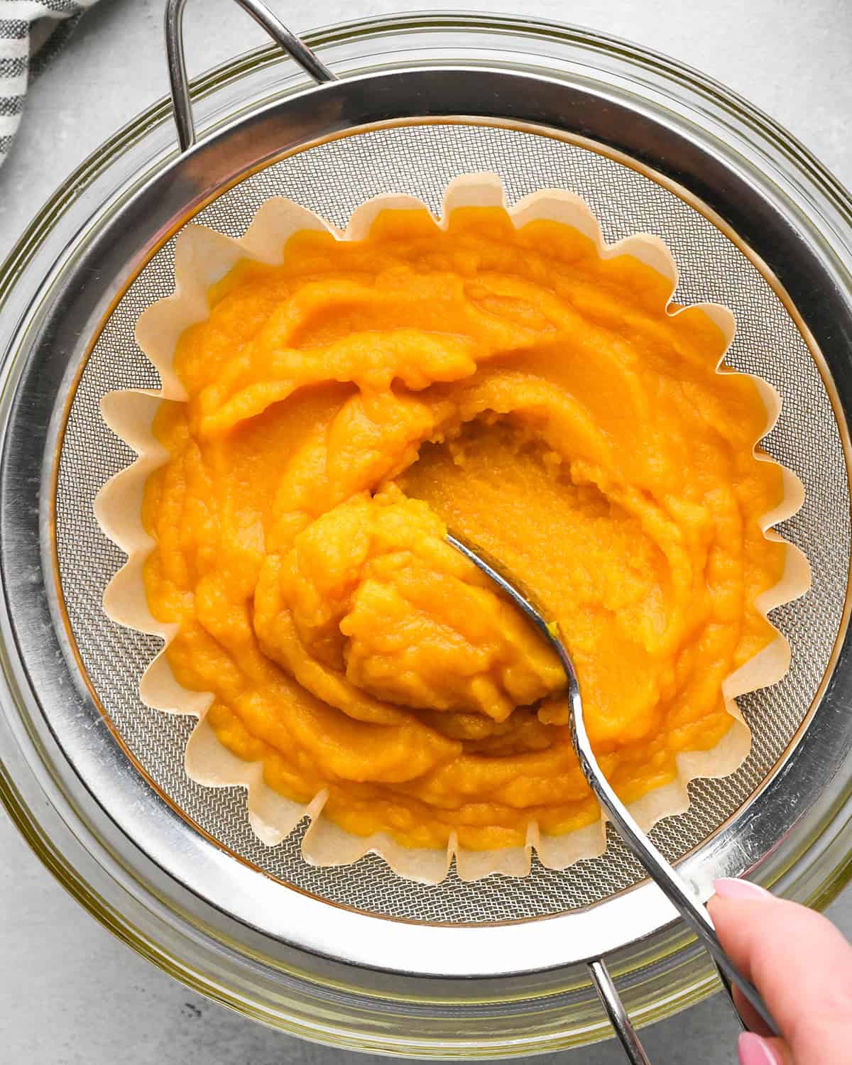 How to Make Pumpkin Puree - pumpkin puree in a strainer after water has been released and it's thickened. 