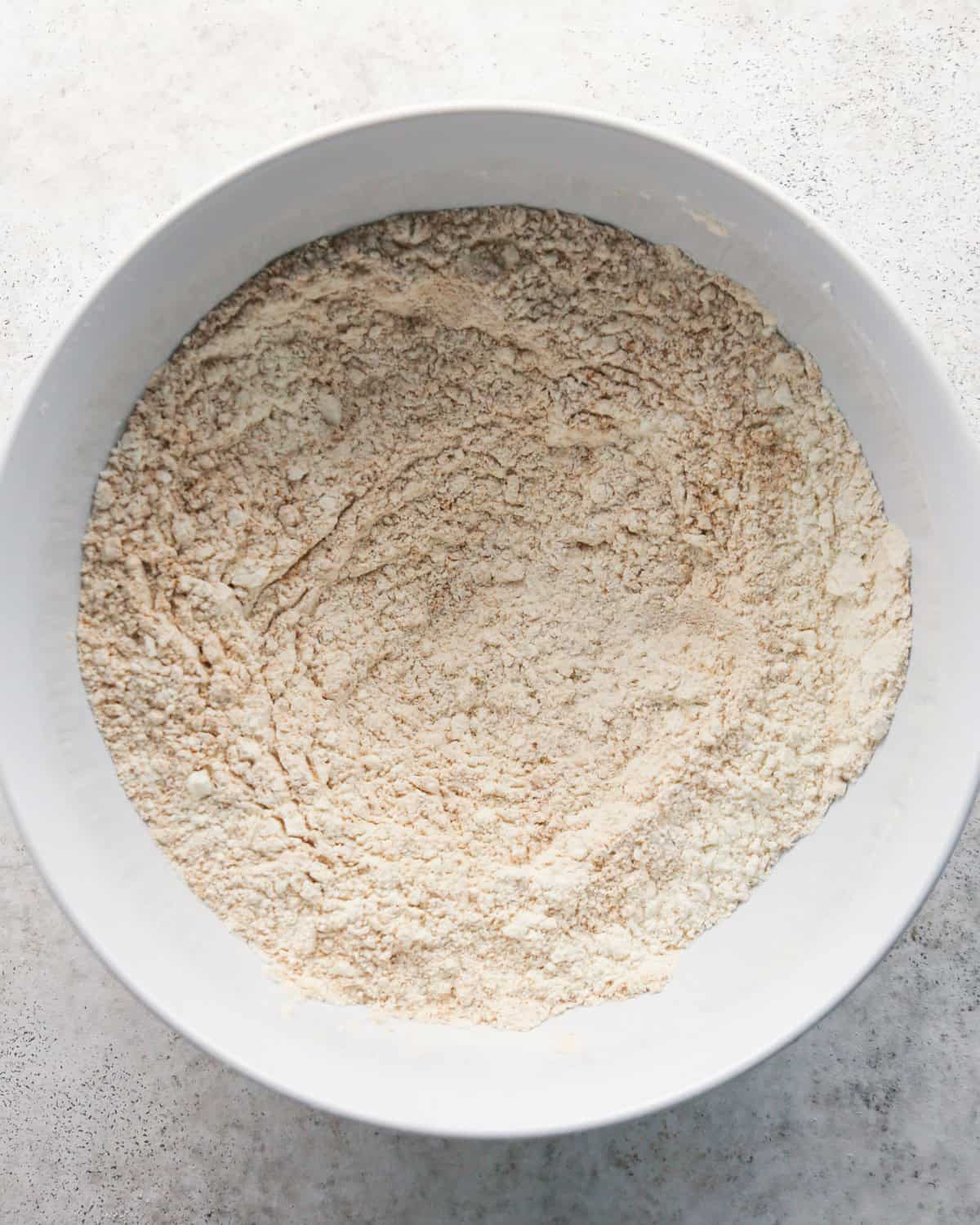 dry ingredient flour mixture in a white bowl on a gray surface making pumpkin snickerdoodles
