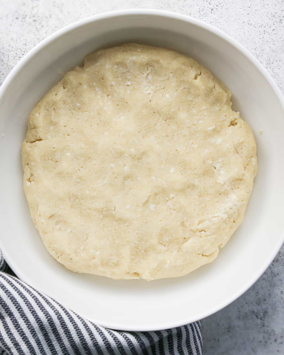 pie crust dough formed into a round disc in a white bowl to be used to make pie crust cookies