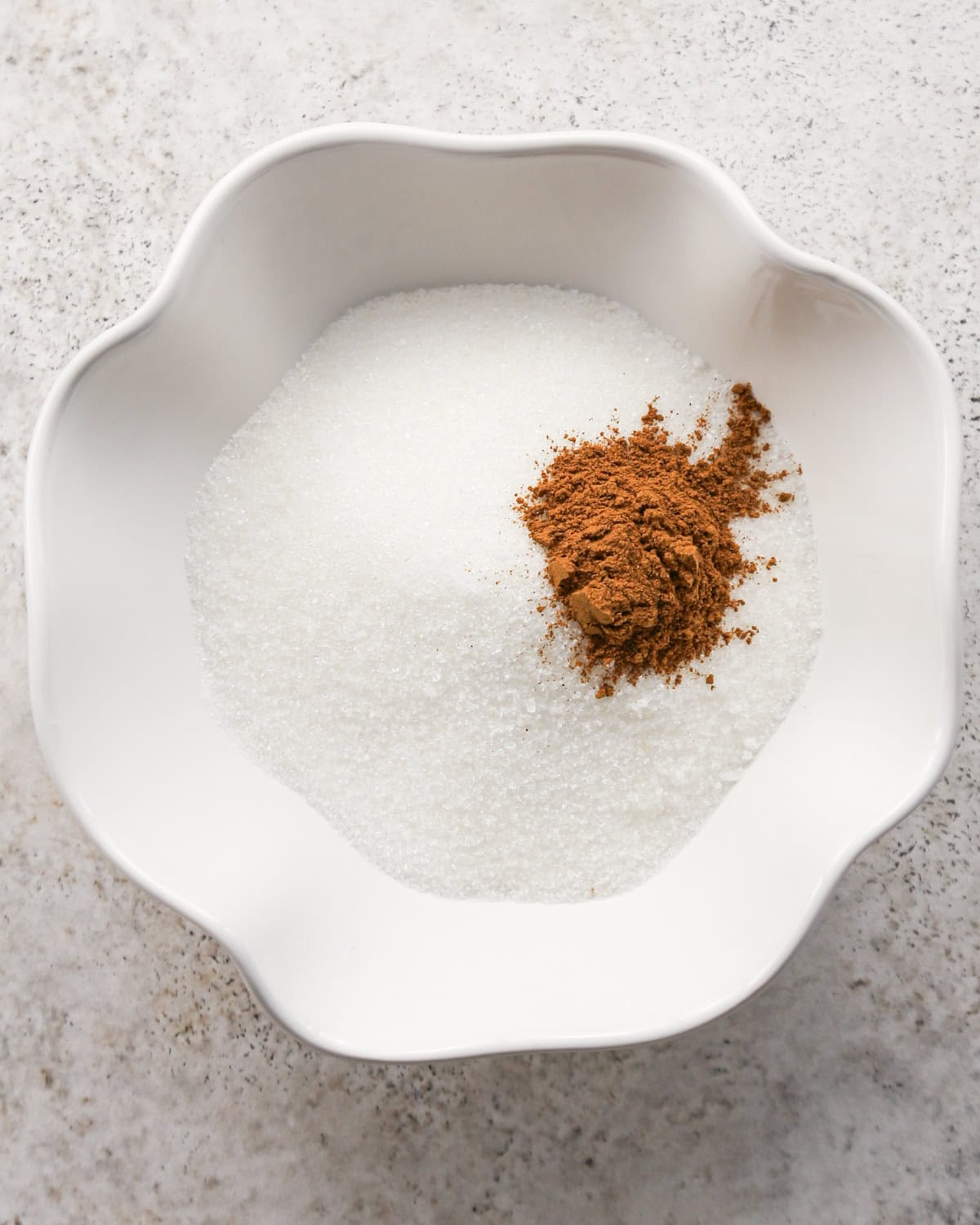 cinnamon and sugar in a small white scalloped bowl before mixing