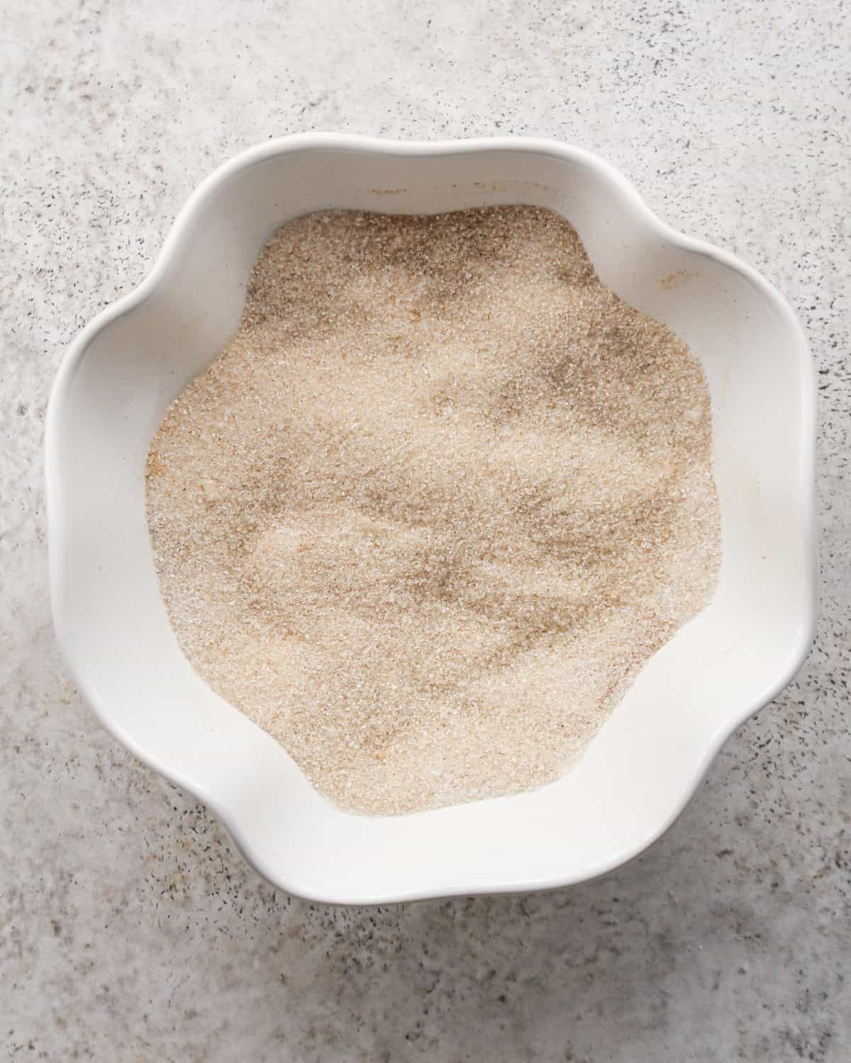 cinnamon and sugar in a small white scalloped bowl after mixing